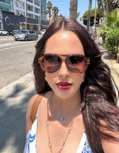 Load image into Gallery viewer, Woman wearing sunglasses on a city street with palm trees and buildings in the background